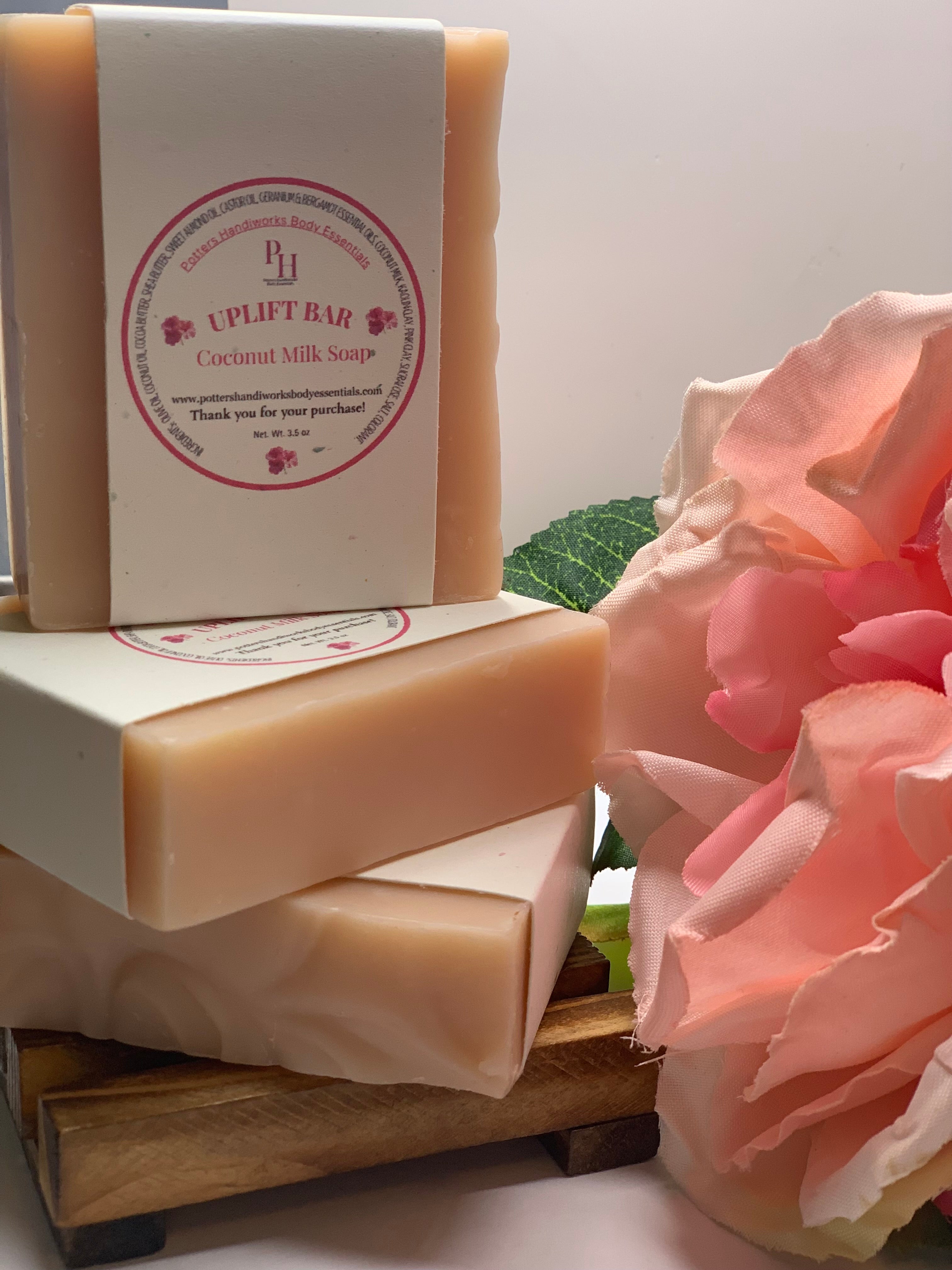 Stack of coconut milk soaps with a pink flower on a white background