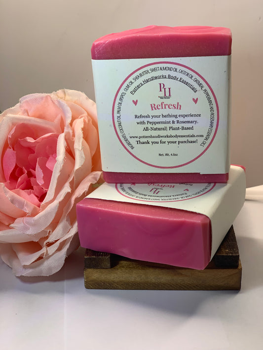 Two pink bars of soap with a wooden soap dish and a pink flower on a white background