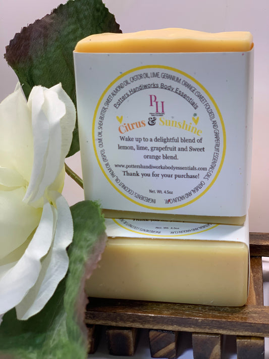 Bar of soap with a label featuring 'P&H' branding, next to a white flower on a wooden surface.