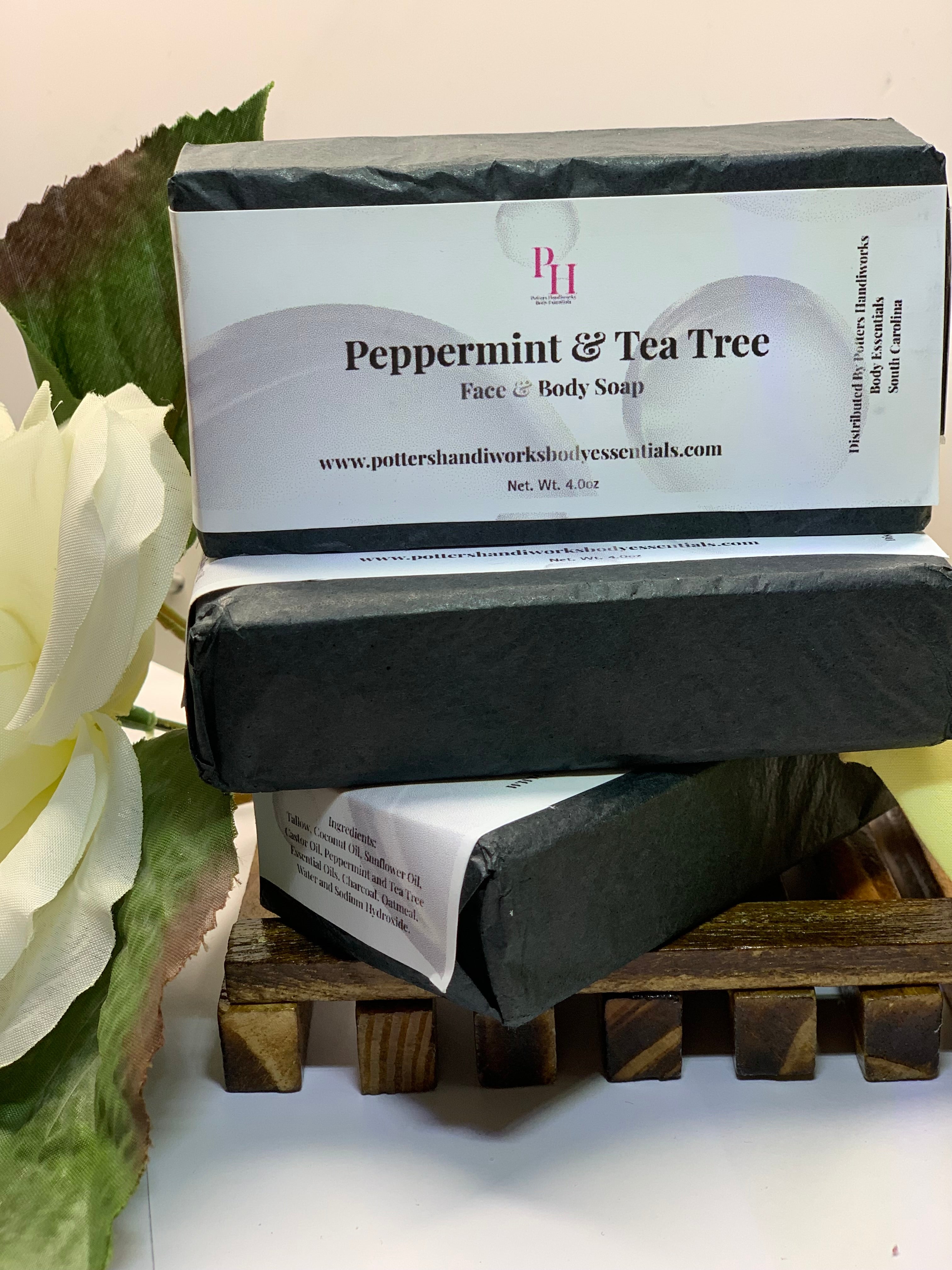 Two bars of peppermint and tea tree soap on a wooden stand with a white flower in the background.